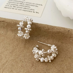 Detailed view of silver hoop earrings featuring intricate geometric multifaceted textures