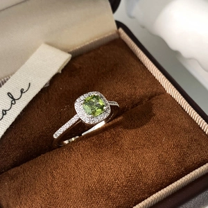 Detail of cushion-cut green zircon ring with micro-paved halo on brown velvet