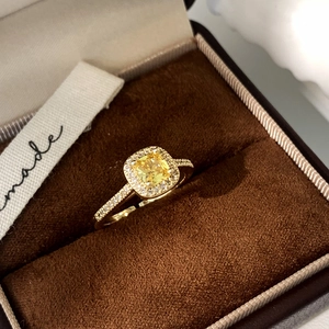 Detailed close-up of a golden adjustable ring with a yellow cushion-cut halo stone