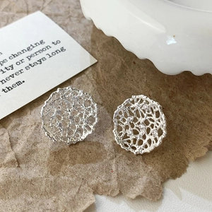 Detailed macro of silver hollow lace earrings with white zircon on craft paper
