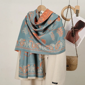 Detail of blue Paisley cashmere-feel scarf with fringes on beige wool coat