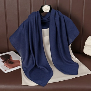 Detail view of navy blue cotton linen scarf draped with a beige silk top and accessories