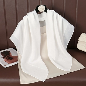 Close-up of white cotton linen scarf draped on a beige top with camellia flower hanger