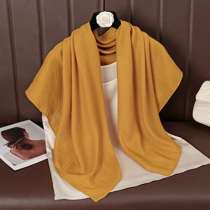Detail of a ginger yellow cotton linen scarf showing soft drape and sheer texture