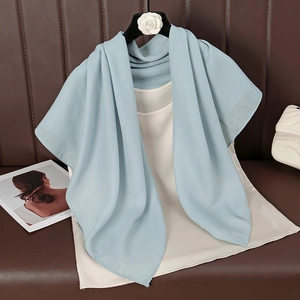 Light blue cotton linen scarf draped on a black hanger over a leather surface