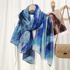 Detail of soft lightweight shawl with blue abstract print draped over a white background