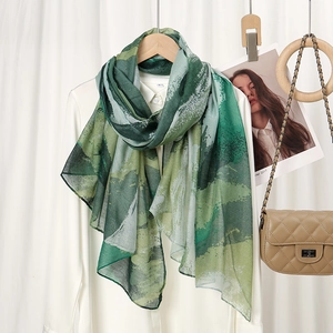 Detail of soft green abstract floral scarf styled with a classic chain handbag