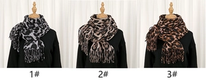 Close-up view showing three different color styles of leopard print tassel scarves.