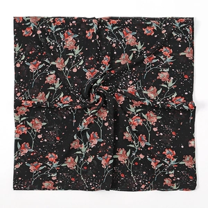 Detail van zwarte chiffon vierkante sjaal met rode en roze bloemenprint