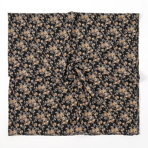 Detailopname van geel bloemmotief op zwarte chiffon stof van een grote vierkante sjaal