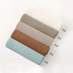 Detail showing various solid earth tones of breathable modal hijab fabrics in neat rolls