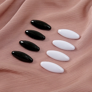 Gros plan détaillé de pinces à hijab magnétiques noires et blanches disposées sur du tissu.