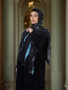 Detail of a lightweight black chiffon hijab with vibrant light blue ethnic tie-dye patterns