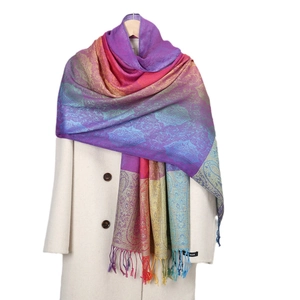 Scialle Paisley sfumato colorato con frange esposto su un cappotto bianco puro