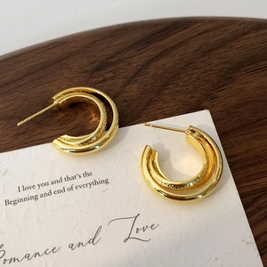 Macro shot of minimalist gold layered geometric hoop earrings on a walnut wood background