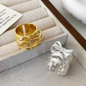 Bow tie open rings in gold and silver finish with brushed metal texture and zircon
