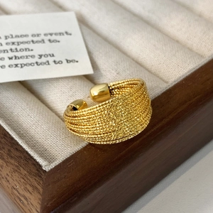 Detail eines strukturierten goldfarbenen Rings mit mehrlagigem Perlen-Design in einer Box