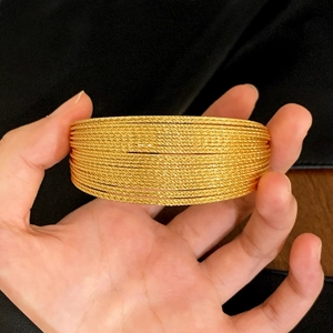 Stack of gold layered bangles with textured spiral design for luxury fashion styling