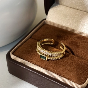Macro detail of a 18K gold double-layer ring with green emerald stone and white zircons