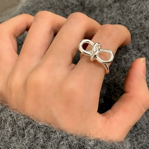 Bague ouverte noeud argentée minimaliste portée élégamment sur le doigt féminin