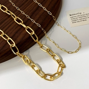 Minimalist gold necklace set with chunky and thin rectangular links on a wooden tray