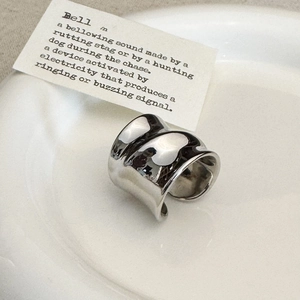 Detail of silver twisted wide open ring with glossy irregular wave texture on white plate