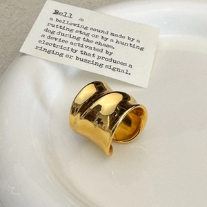Polished gold irregular wide band ring with minimalist mirror finish on ceramic plate