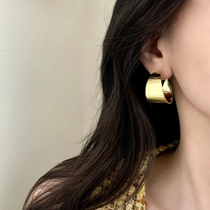 Polished gold wide-hoop metal earrings with a glossy finish for a minimalist chic look