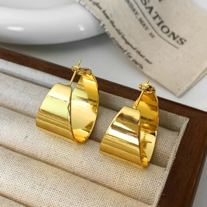 Macro shot of polished gold chunky C-shaped hoop earrings on a velvet display tray