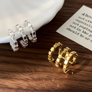 Minimalist gold and silver C-shaped geometric cube ear cuffs on a wooden background