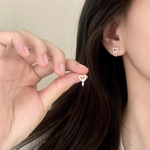 Elegant silver heart earrings with white crystals shown worn on a model's ear