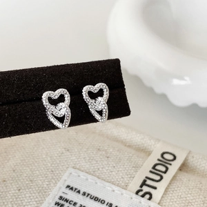 Macro shot of silver interlocking heart earrings with beaded texture on velvet display