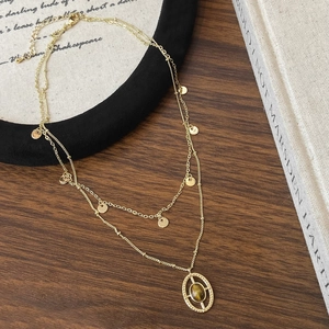 Detail of a vintage double-layer gold necklace featuring tiger eye stone and coin charms