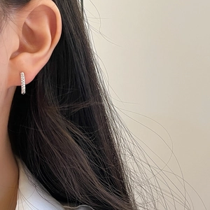 Gros plan d'une boucle d'oreille créole torsadée en argent avec un motif de tresse
