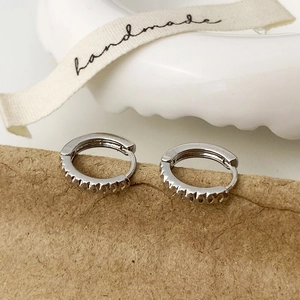 Gros plan détaillé de boucles d'oreilles huggie argentées avec gravure dentelée unique