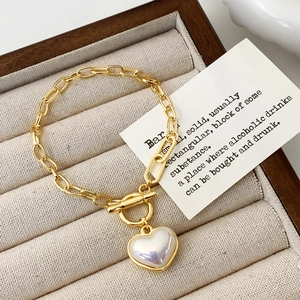 Elegante bracciale dorato con ciondolo a cuore e chiusura a T su portagioie