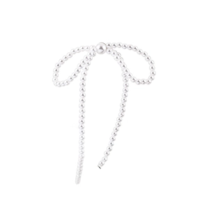 Elegant pearl bow earrings featuring high-luster round white pearls on a minimalist white backdrop