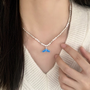 Detail of blue whale tail pendant and mixed pearl beaded necklace on model
