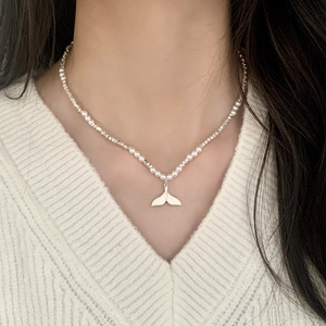 Elegant pearl and silver bead necklace with a sleek fishtail pendant on a model