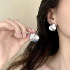 Polished silver textured round stud earrings featuring a cross-hatched leather-like pattern