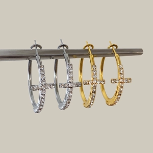 Dettaglio di orecchini a cerchio in oro e argento con croci in zircone su supporto