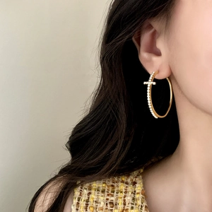 Elegant gold cross hoop earrings with sparkling cubic zirconia on a female model