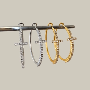Detailed view of silver and gold hoop earrings with sparkling zircon cross pendants
