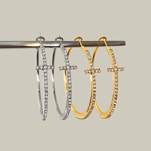 Dettaglio di orecchini a cerchio in oro e argento con croce di zirconi brillanti