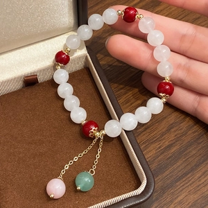 Detailed shot of beaded bracelet with red stones and elegant golden double tassels