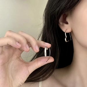 Minimalist silver heart-shaped earrings on model with elegant light beige background