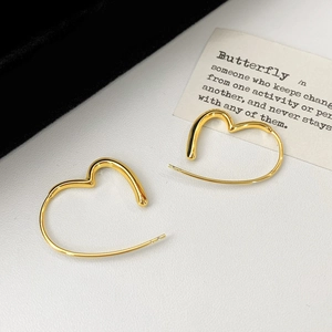 Macro shot of minimalist gold heart-shaped hoop earrings on a textured background