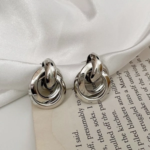 Macro shot of silver triple-interlocked hoop earrings on elegant satin fabric