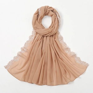 Detail eines kamelfarbenen Schals mit feiner weißer Spitzenstickerei und Chiffon-Stoff