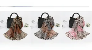 Three leopard print chiffon scarves in brown, grey, and pink draped on a handbag